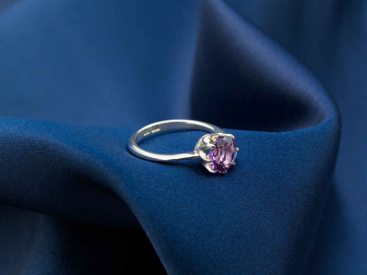 A sterling silver ring with a purple amethyst gemstone in a crown setting