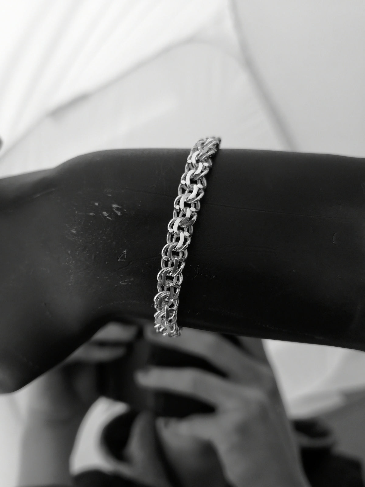Hand-crafted Sterling Silver chain bracelet on a mannequin arm against a blurreed background