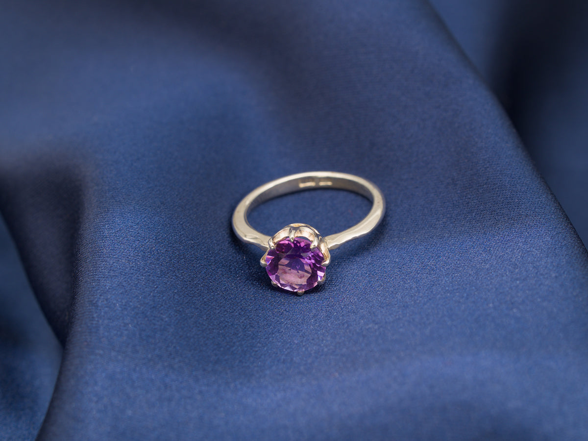 A sterling silver ring with a purple amethyst gemstone in a crown setting