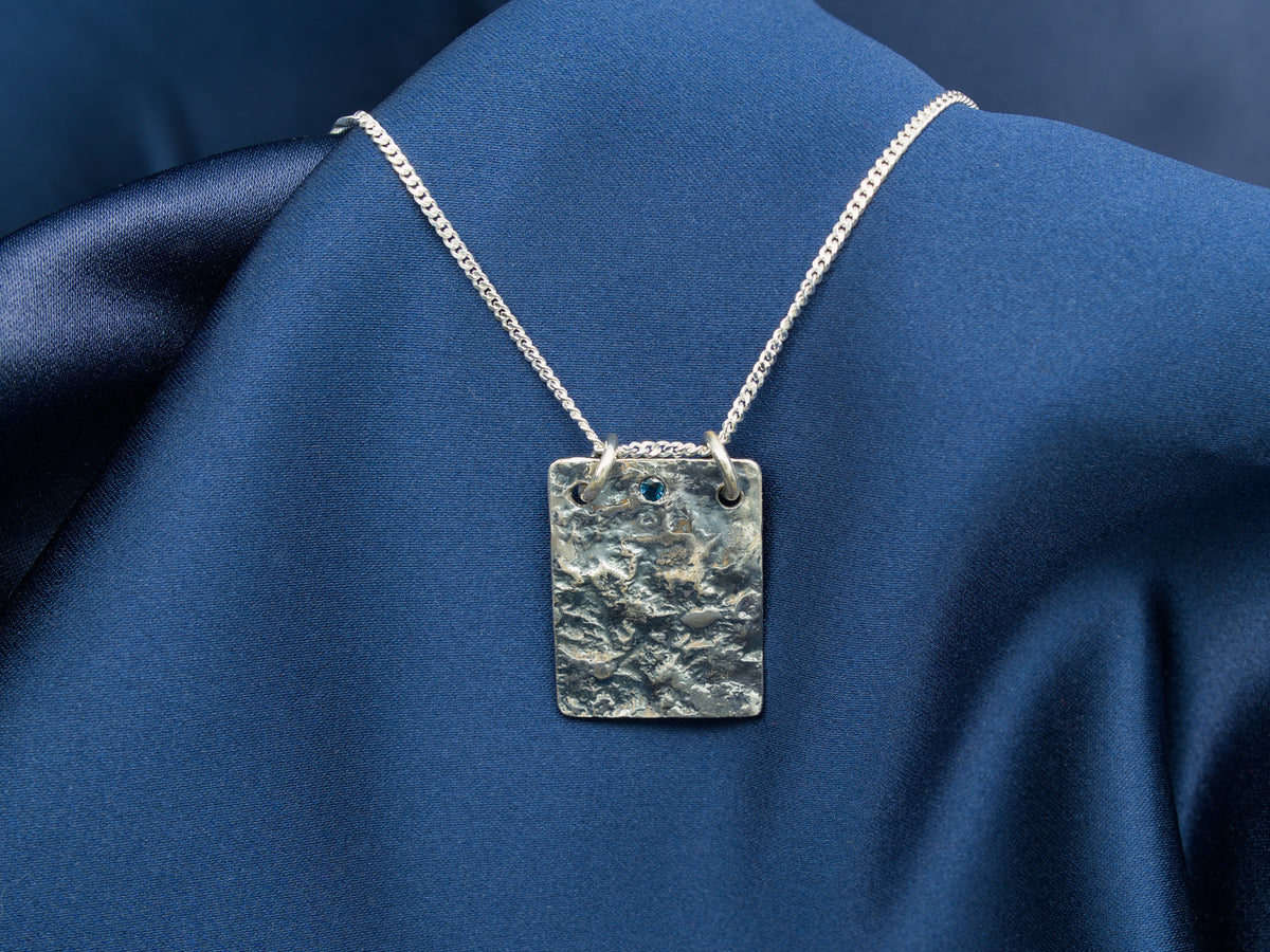 Reticulated sterling silver necklace with a blue sapphire gem