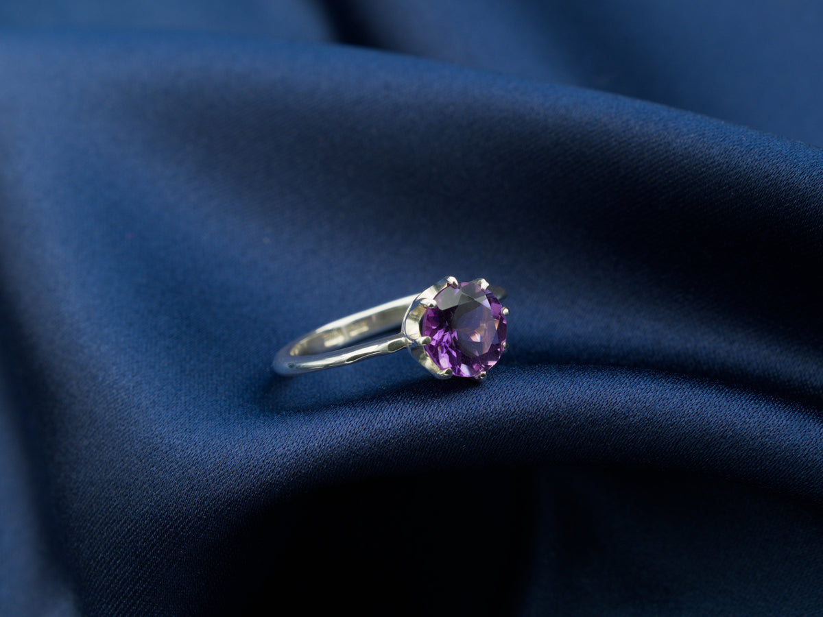 A sterling silver ring with a purple amethyst gemstone in a crown setting
