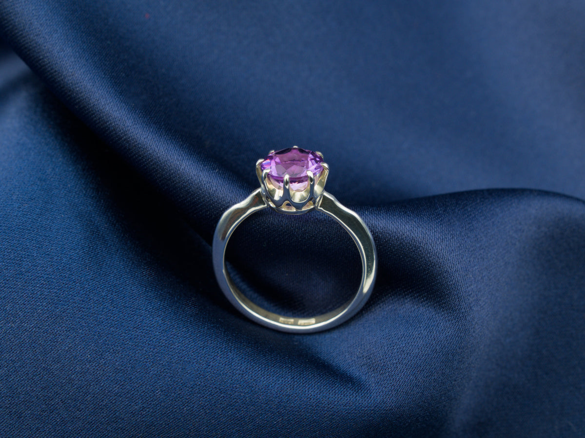 A sterling silver ring with a purple amethyst gemstone in a crown setting
